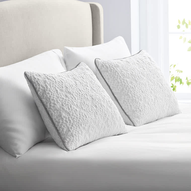 Four white pillows atop a bed