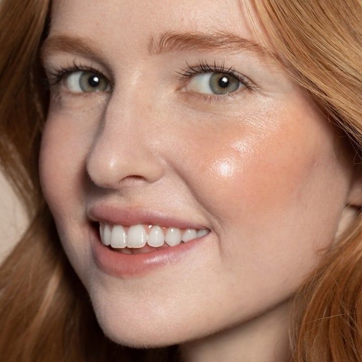 model wearing orange-y cream blush stick