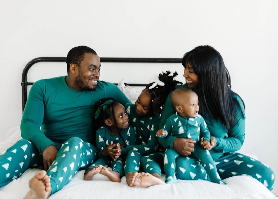 family of five wearing matching green long-sleeves with leggings that have white christmas trees on them