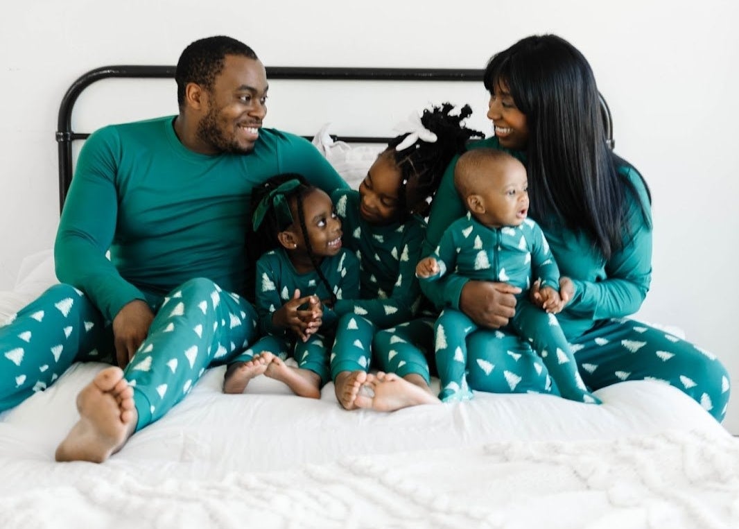 family of five wearing matching green long-sleeves with leggings that have white christmas trees on them