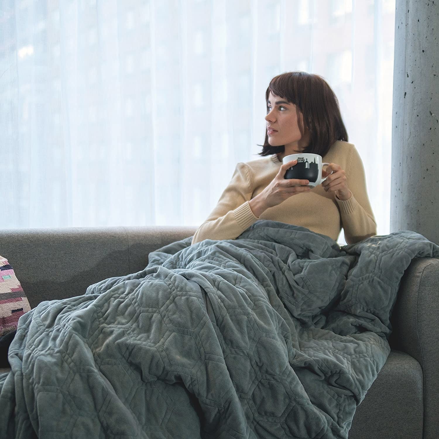 A person lying on a couch under the weighted blanket