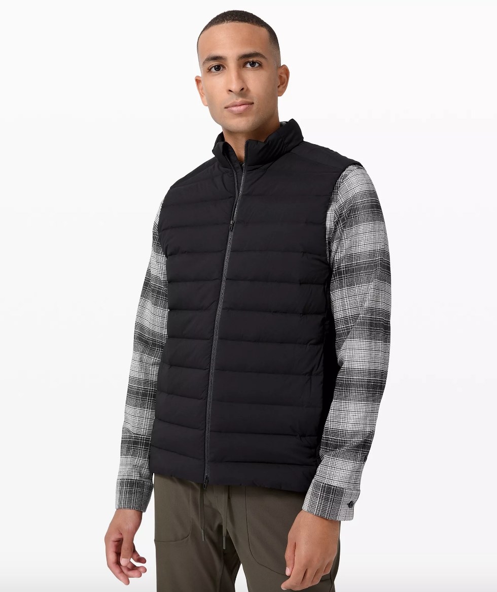 Model wearing black vest over flannel shirt