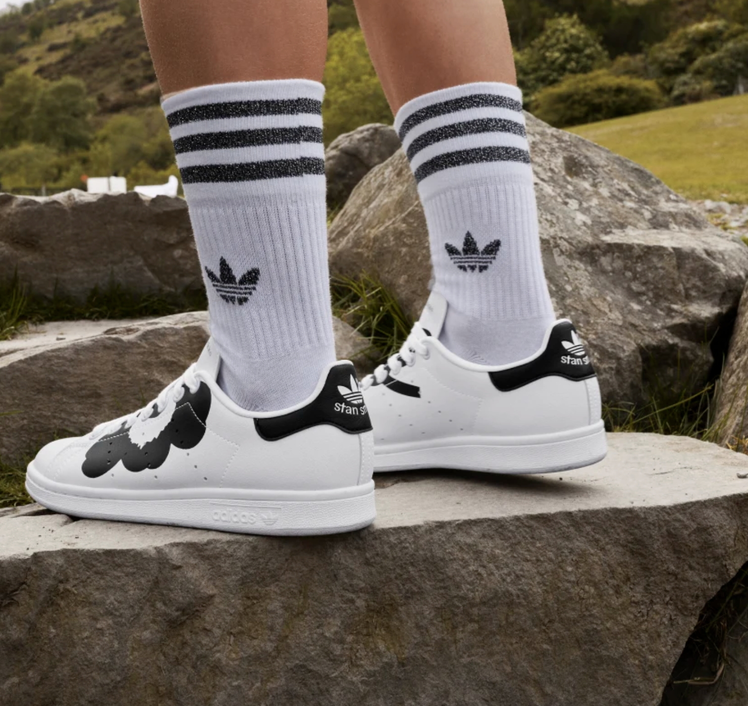 A person wearing the sneakers with crew socks while standing on a rock