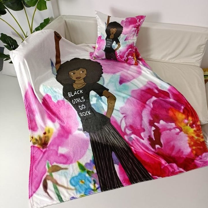 throw with a floral background and an illustration of a girl with a big afro and a t-shirt that says "Black Girls do Rock" on the front plus a matching pillow
