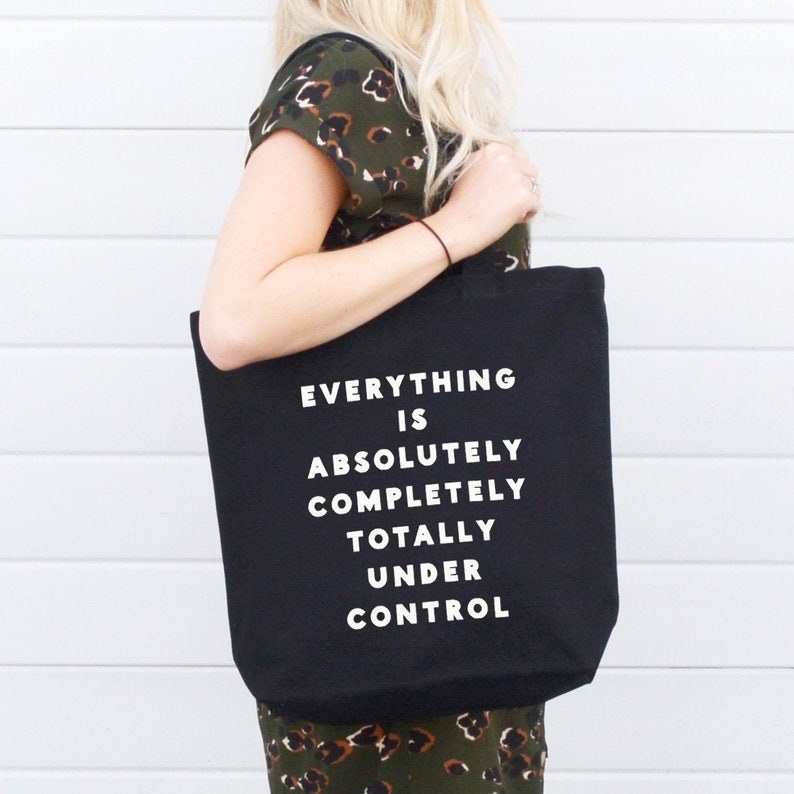 model wearing black tote bag that says &quot;everything is absolutely, completely totally under control&quot;