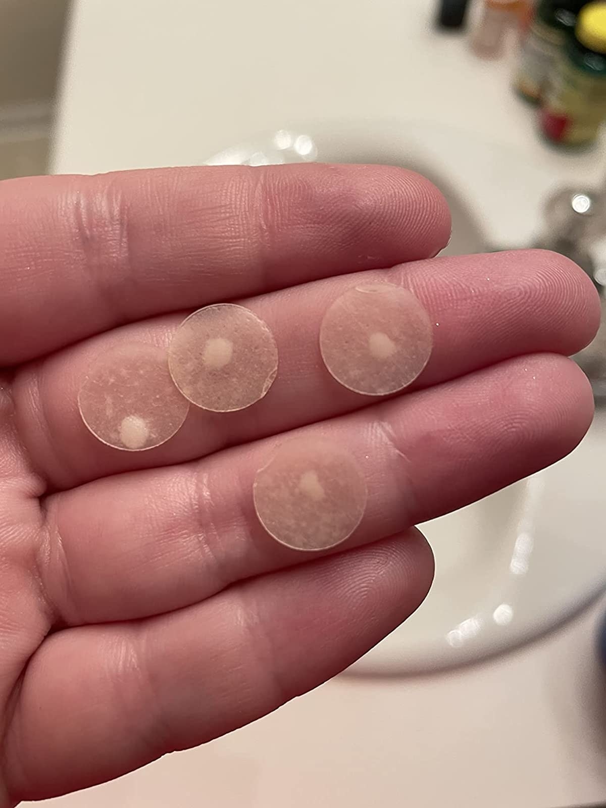 reviewer&#x27;s hand holding a few loaded acne patches