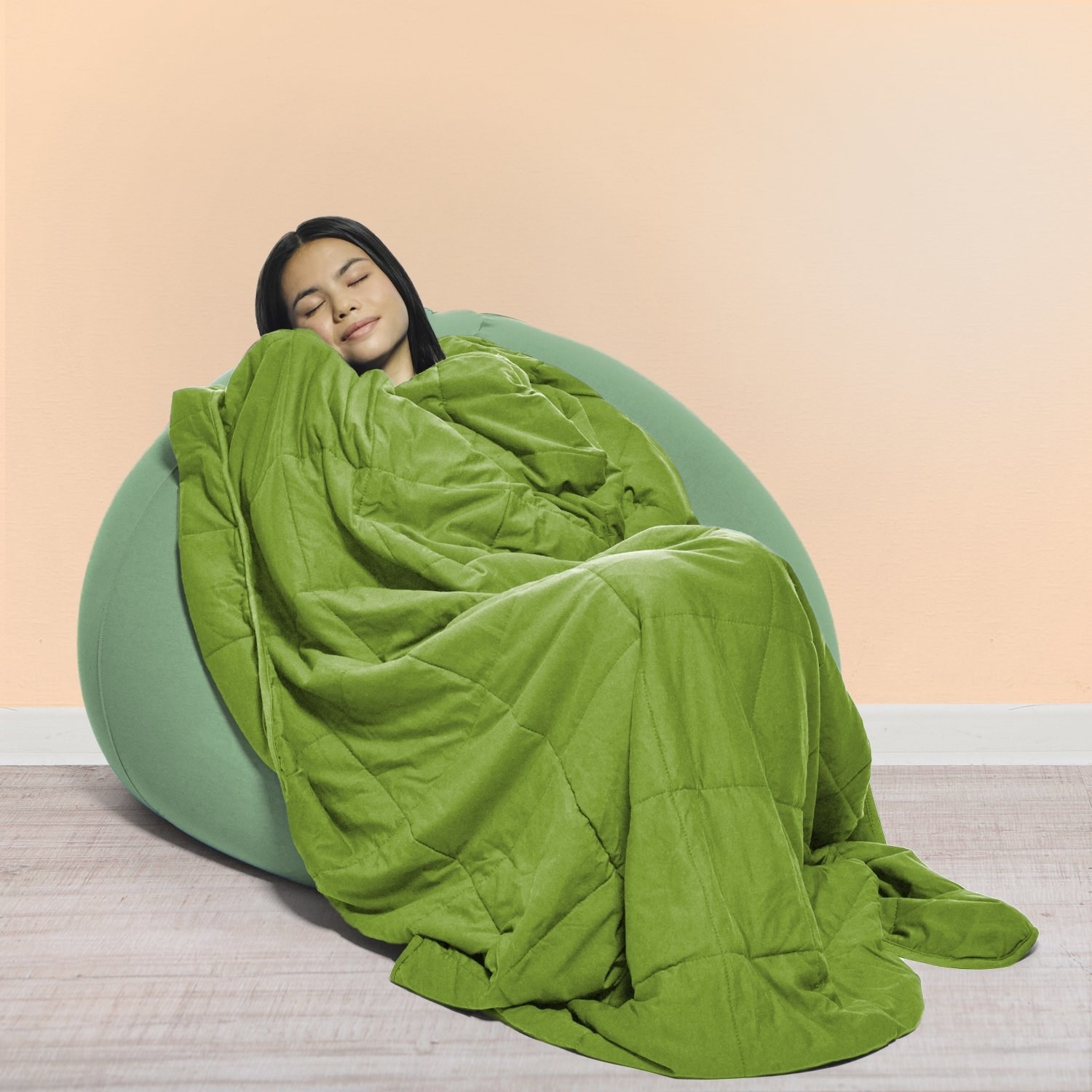 Model snuggled in a chair under a green blanket