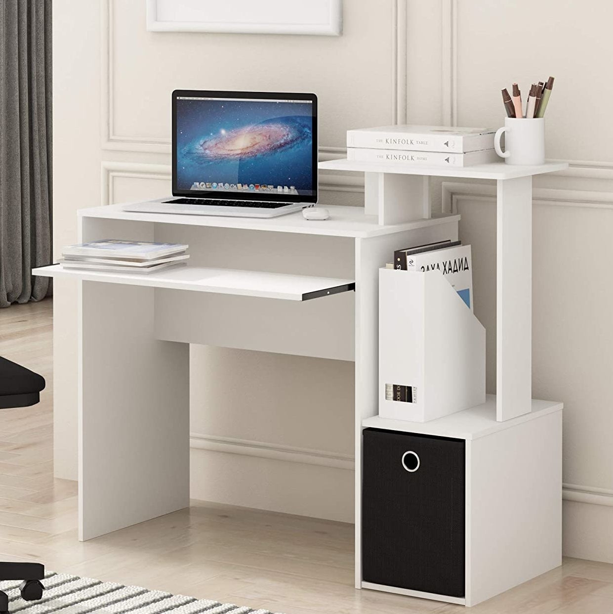 The computer desk with a laptop, books, and files on it