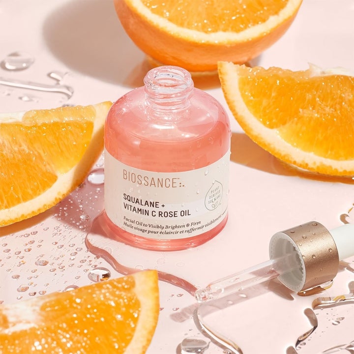 a bottle of the Squalane + Vitamin C Rose Oil surrounded by orange slices