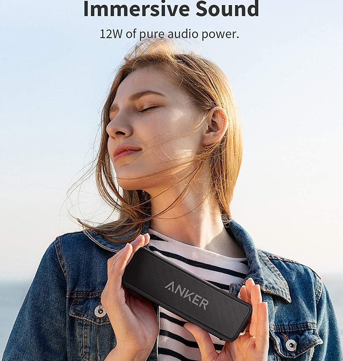 A person holding a rectangular portable speaker