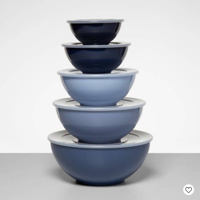A set of five blue mixing bowls with lids stacked on each other
