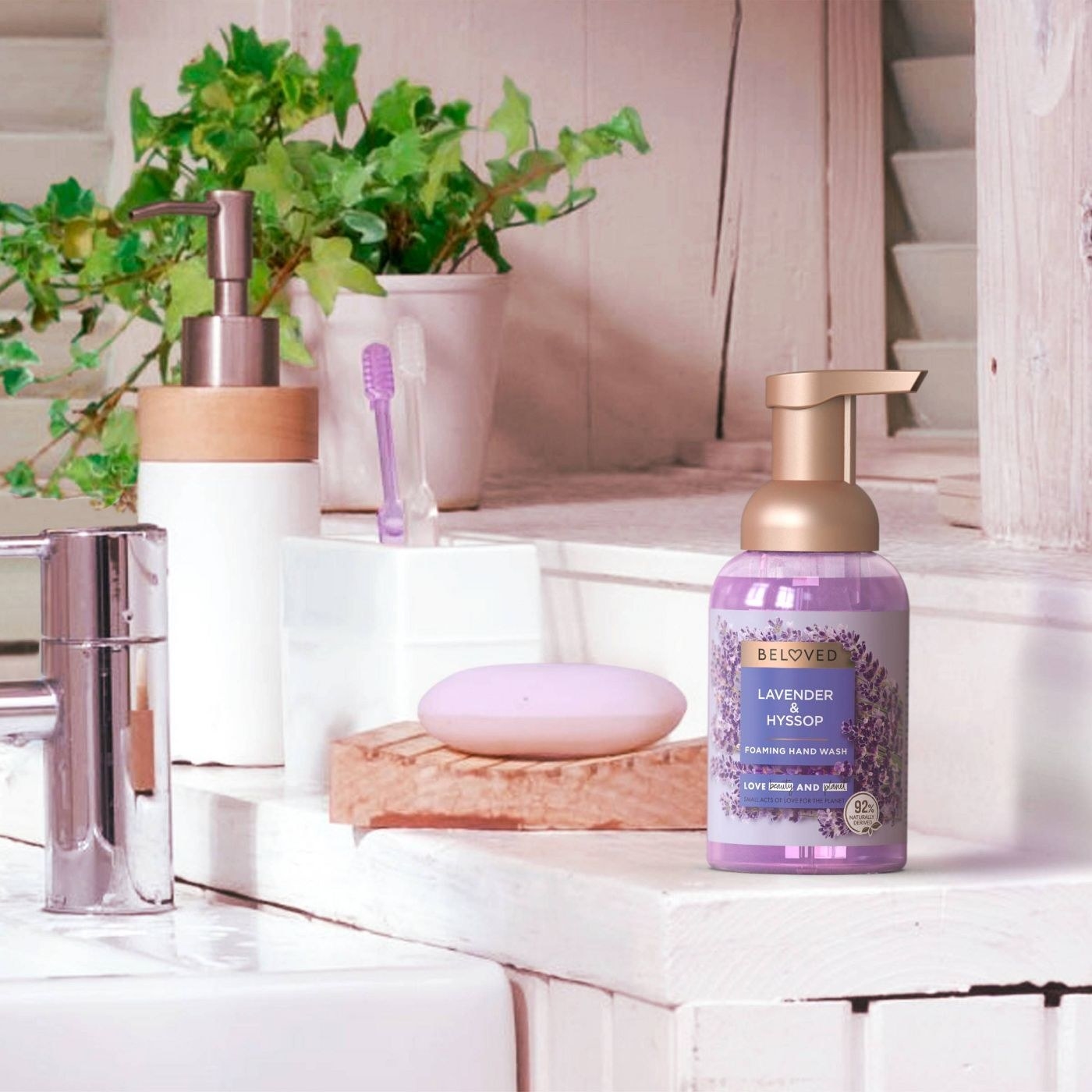 A gold-pumped lavender soap sits on a bathroom with lavender colored bar soap and toothbrushes