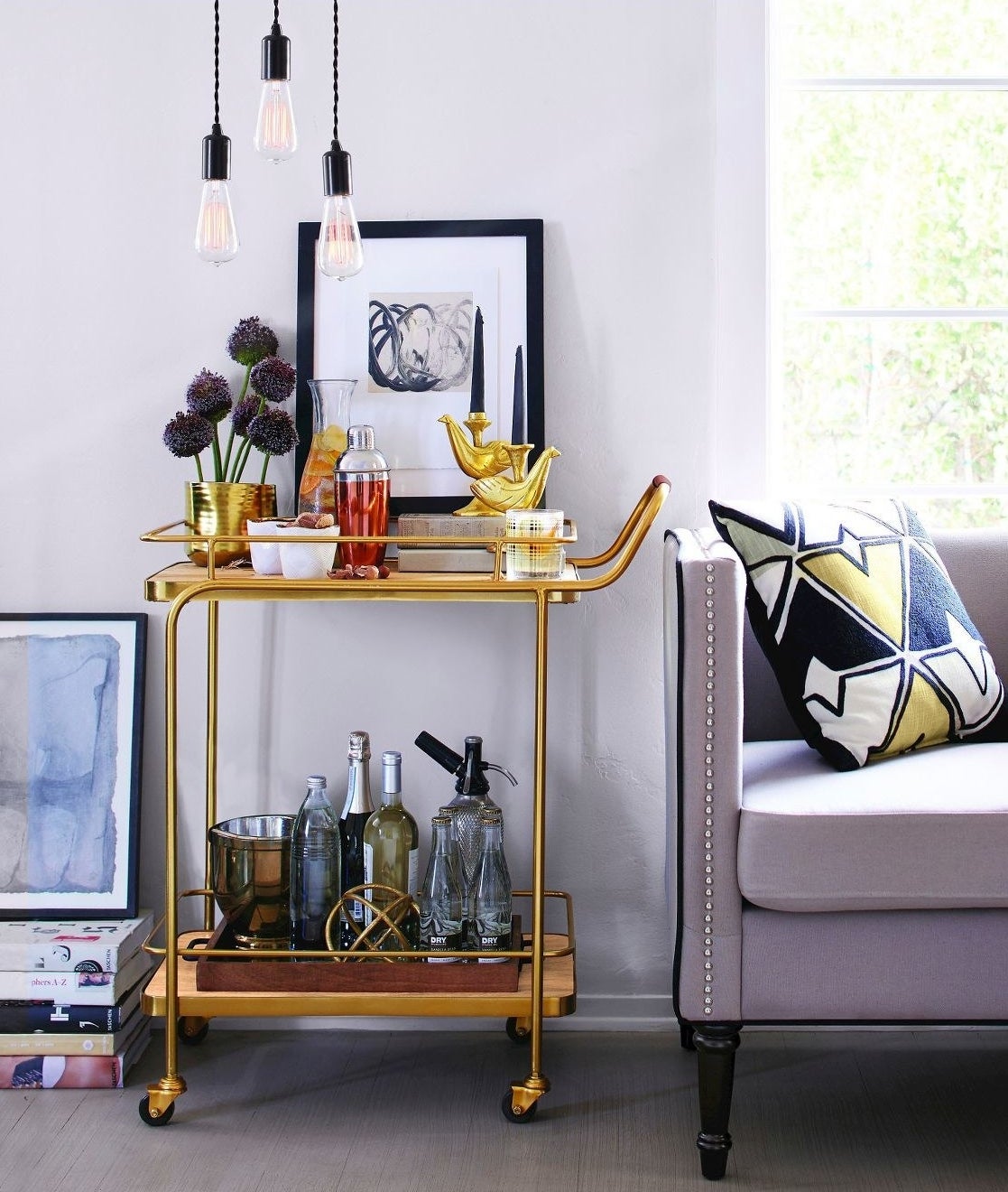 A stocked gold bar cart sits next to a couch