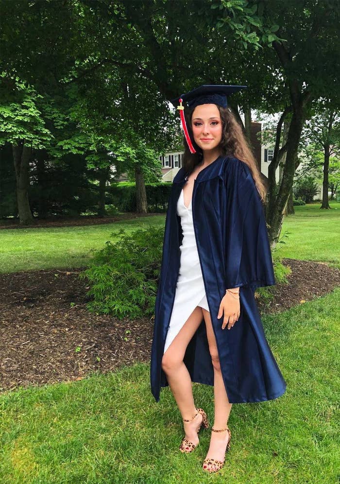 Natalia standing on the grass wearing a graduation gown and hat and sandals