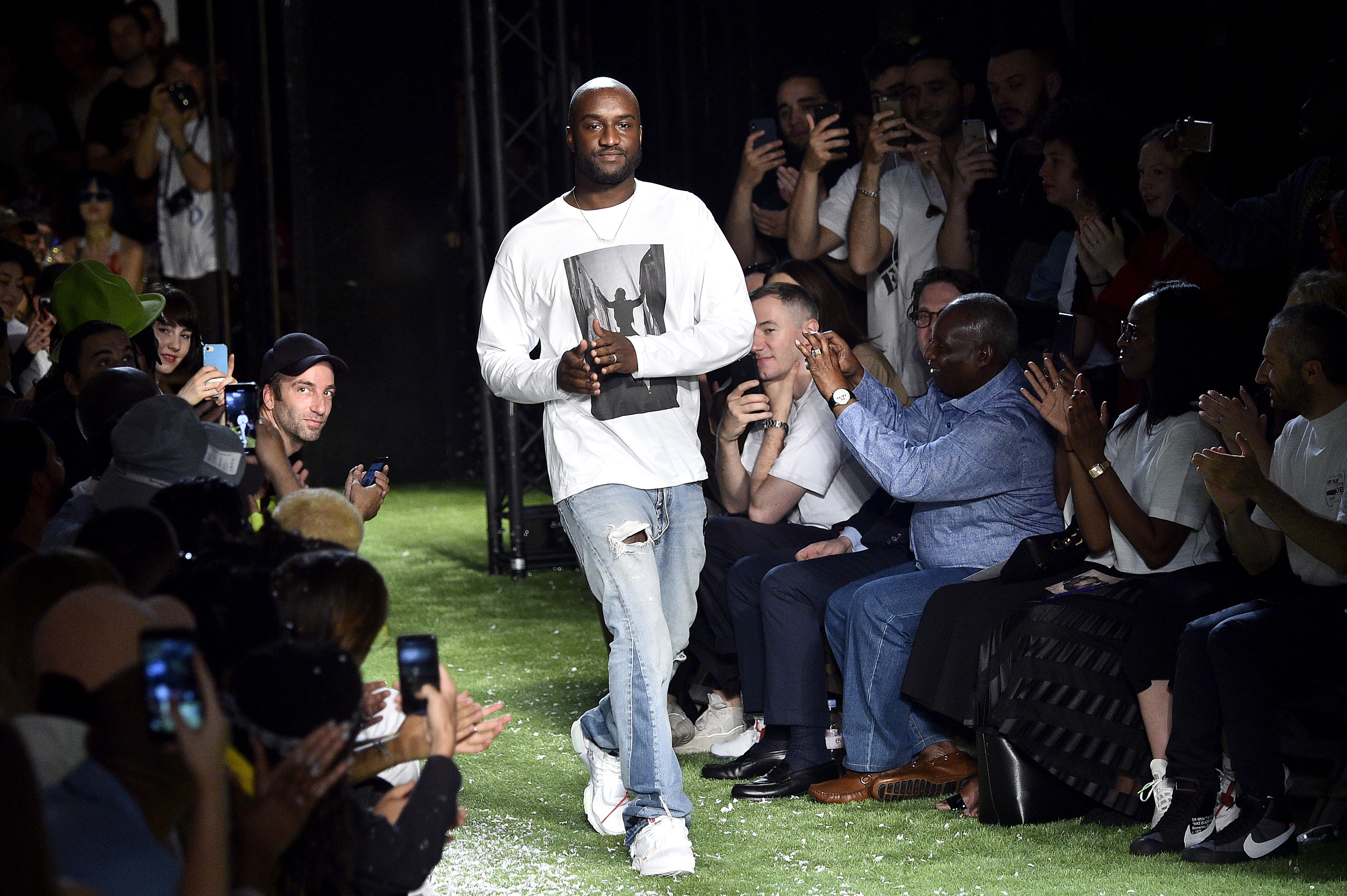 Man wearing jeans and a long-sleeved T-shirt walks amid an audience