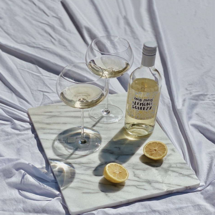 Image of wine bottle next to glasses and cut lemon