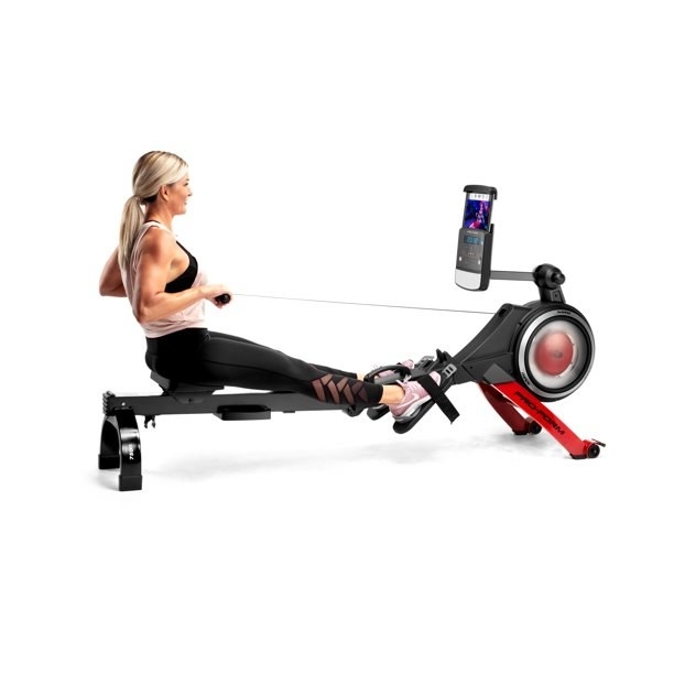 Model exercising on red and black rowing machine