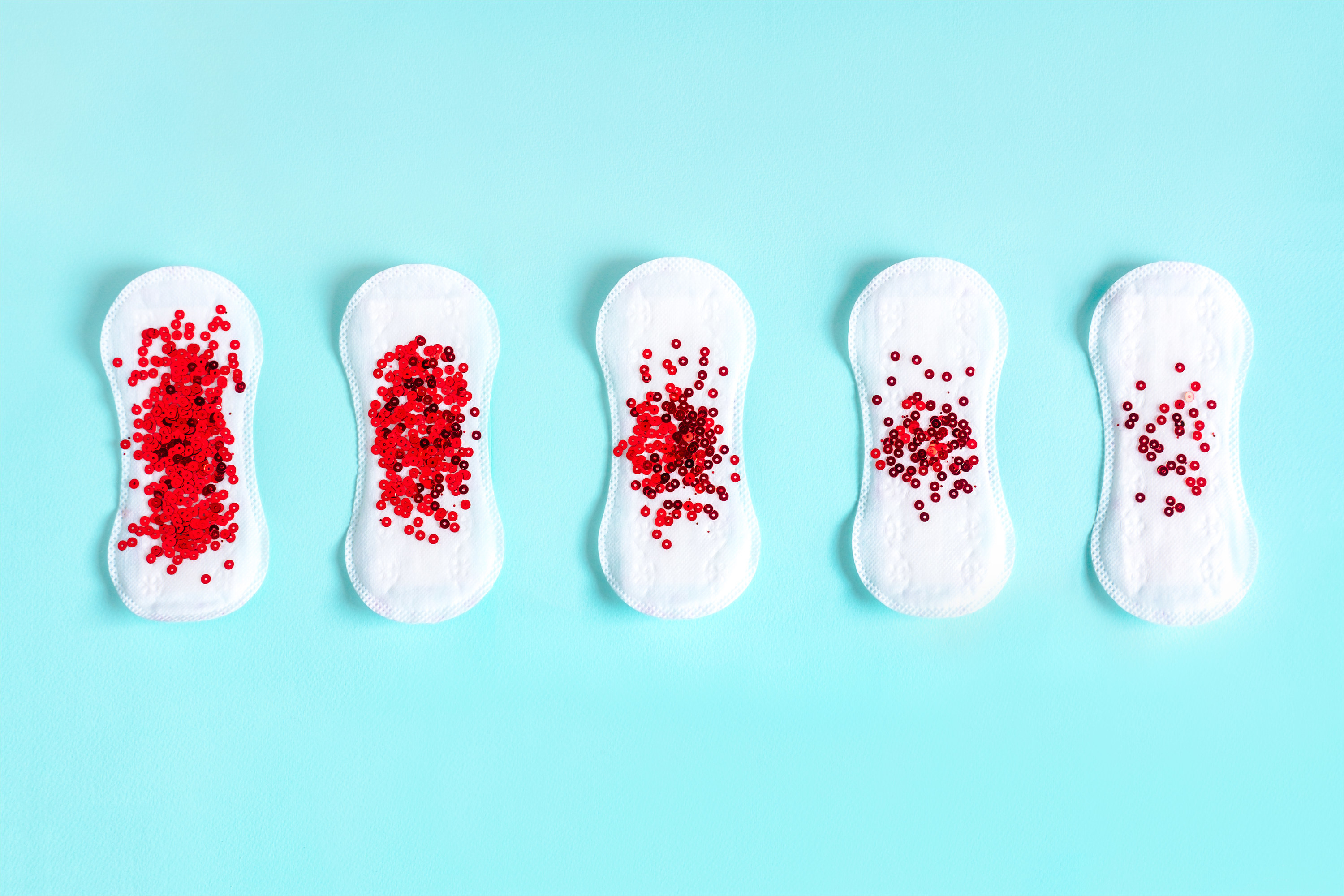 A line of sanitary pads with different amounts of red sequins designed to look like blood