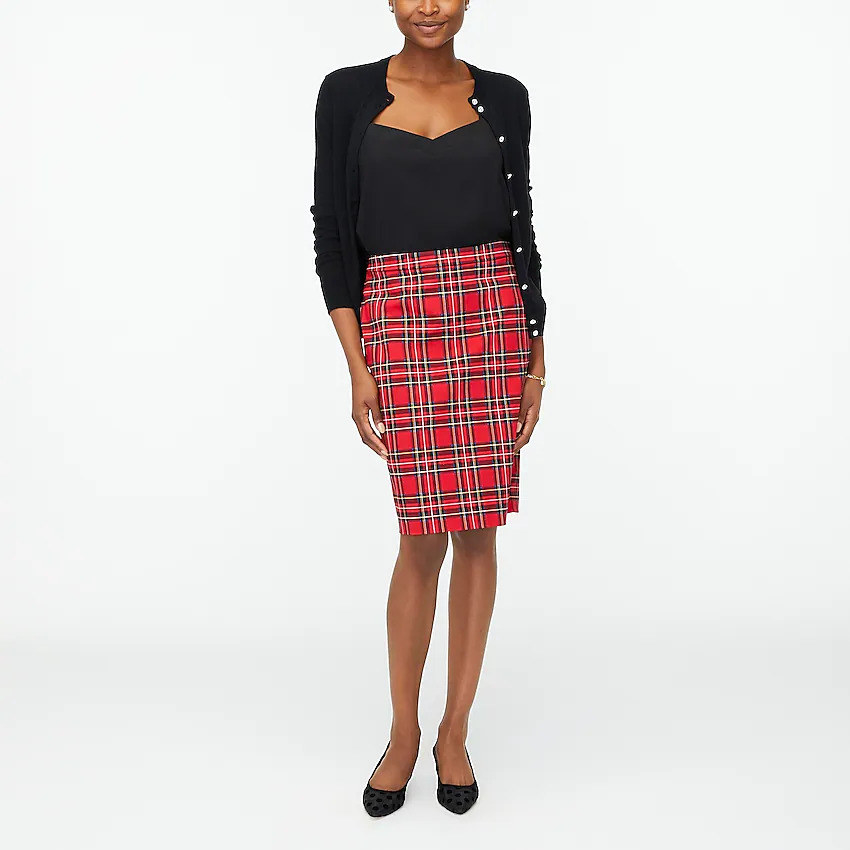 a model wearing the red plaid pencil skirt with a black tank top tucked in and a black cardigan