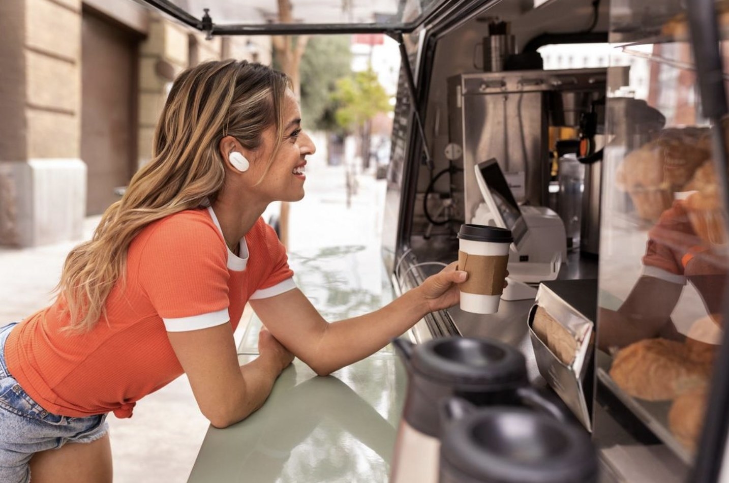 Female wearing the white earbuds while order coffee