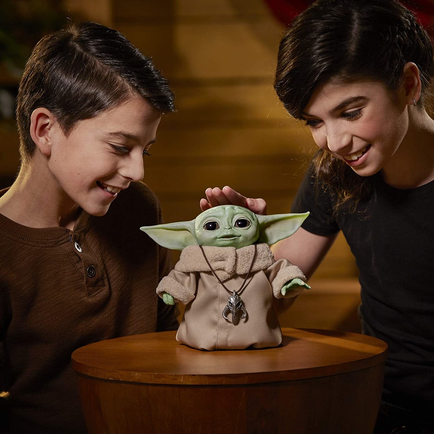 Two people patting the Yoda doll on the head