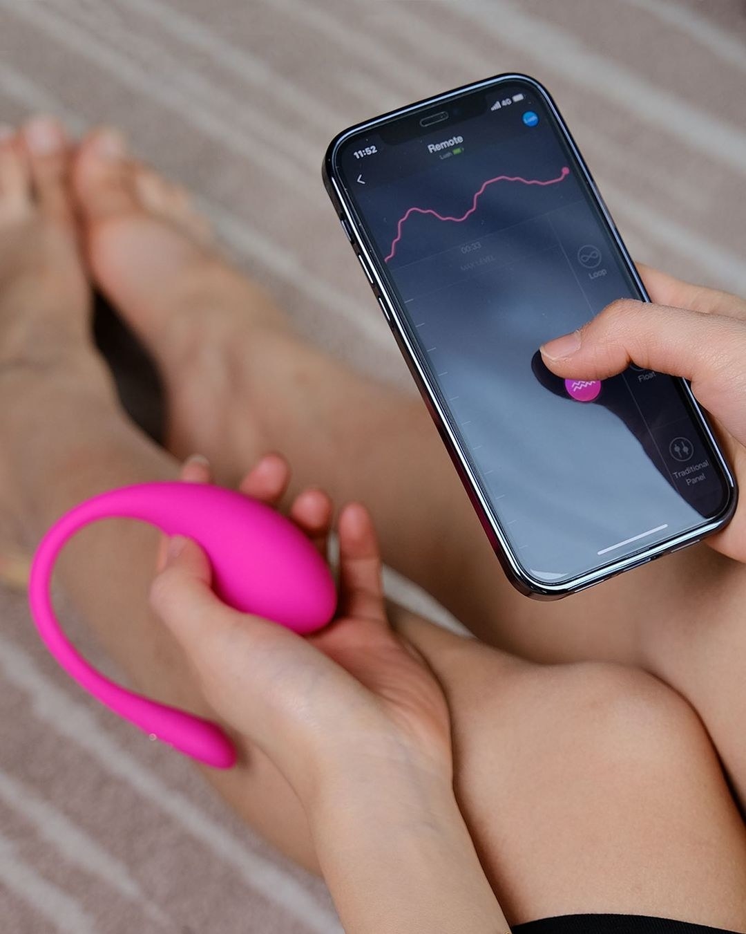 Model holding pink egg vibrator and demonstrating app on cell phone