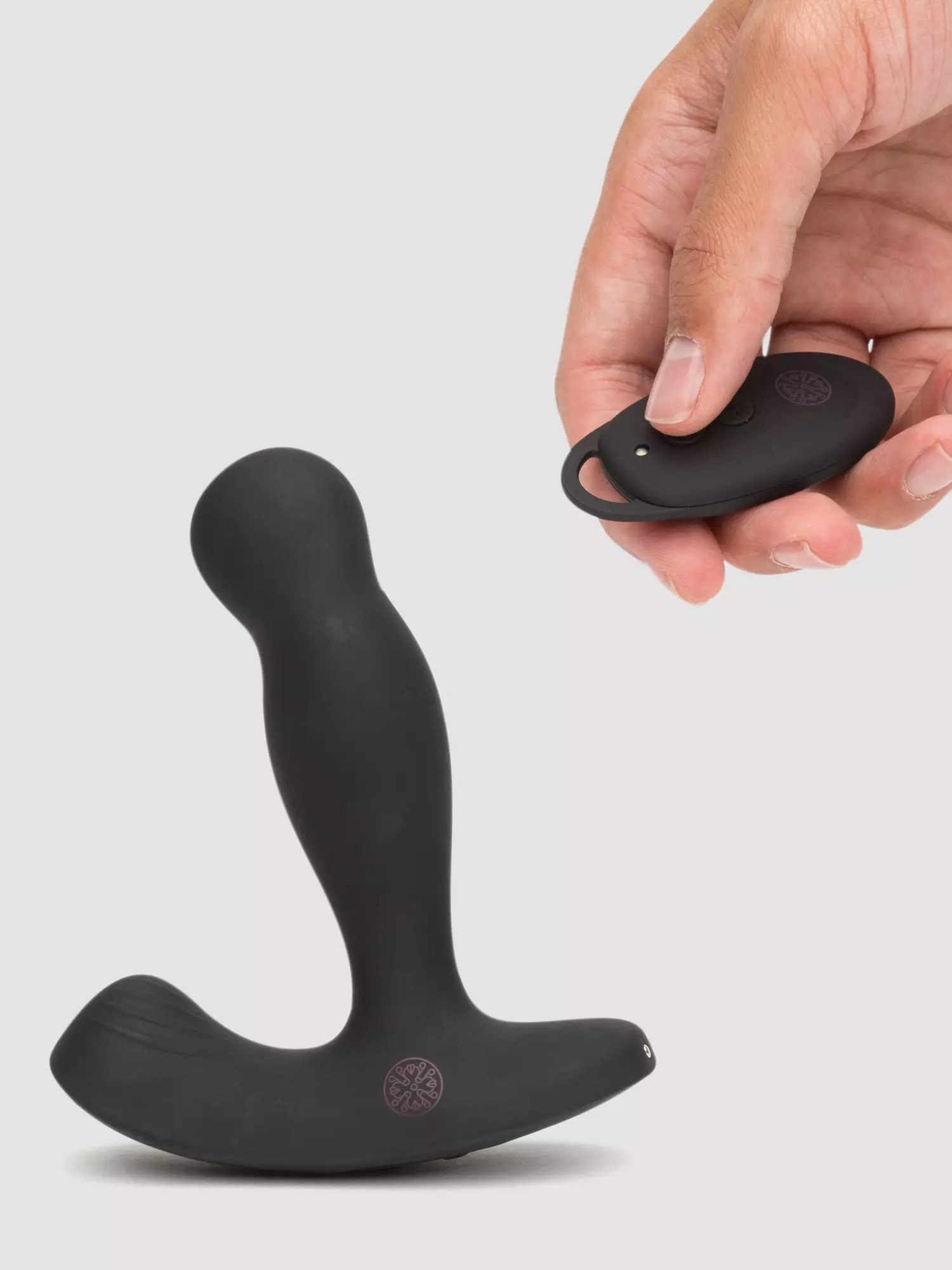 Black prostate plug and hand holding black wireless remote