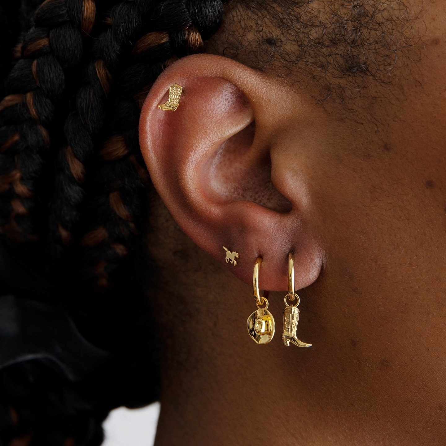 A gold cowboy earring set on a model
