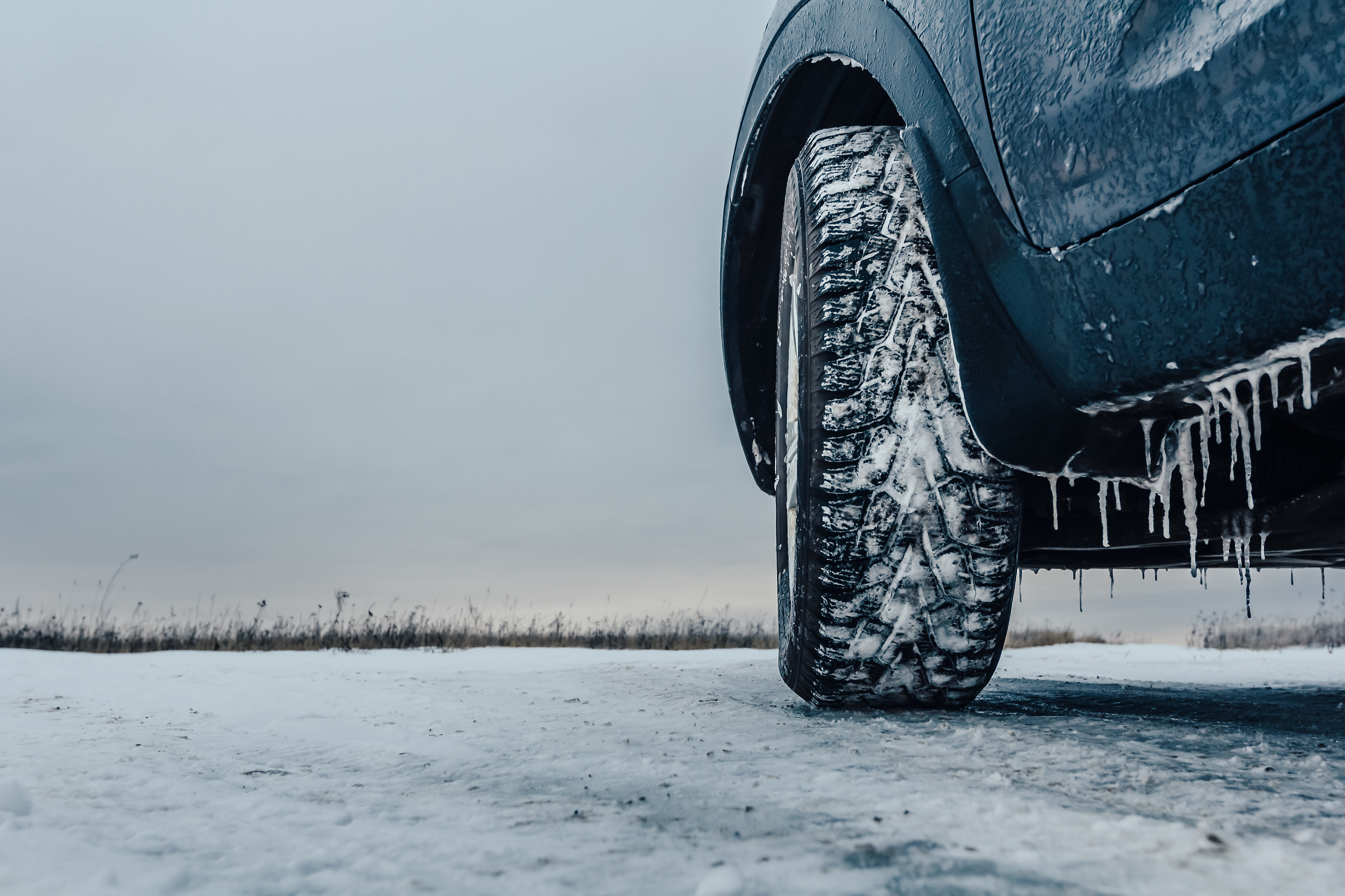a low view of a car&#x27;s tires with snow and ice