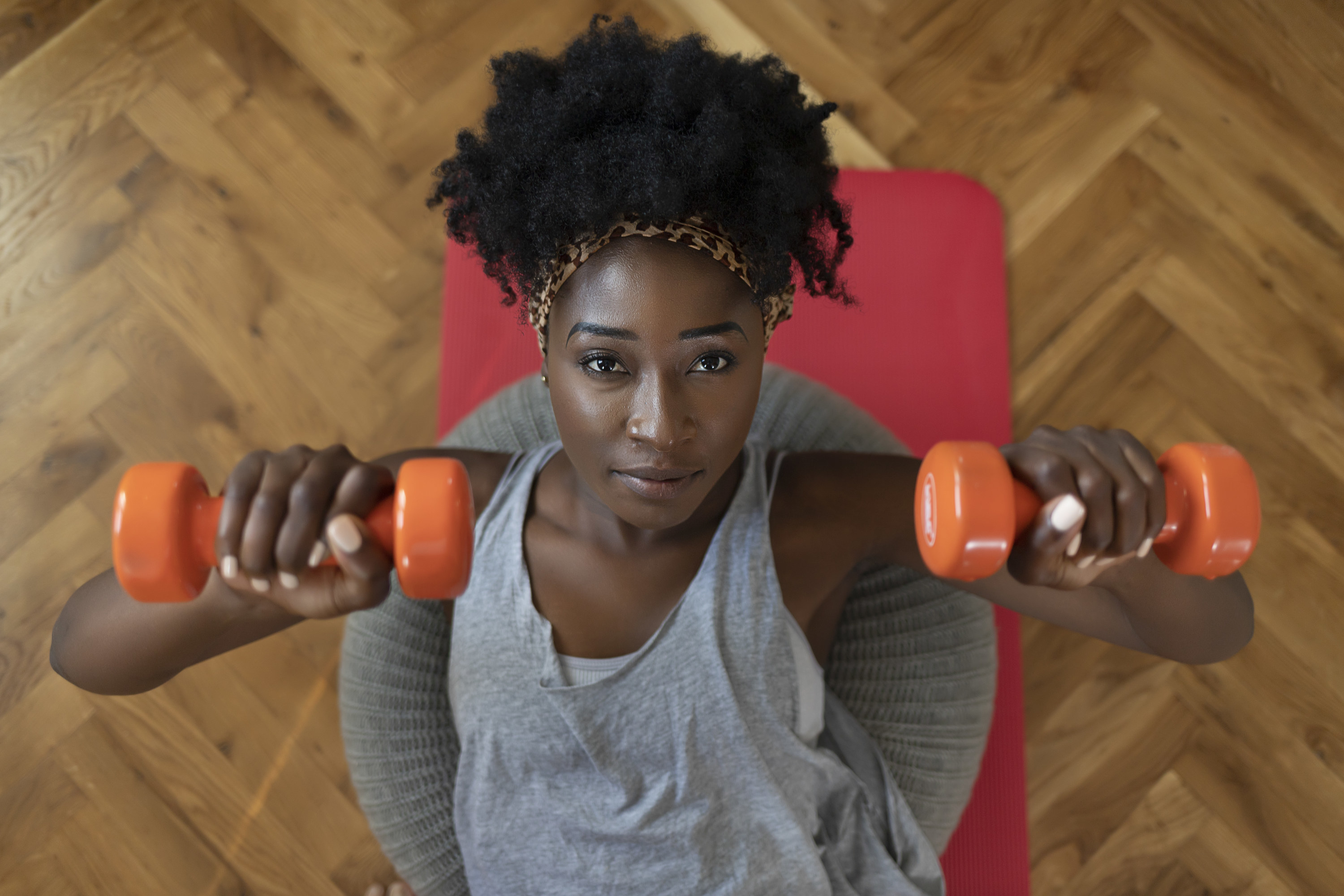 A woman lying on a yoga mat holding dumbbells in each hand