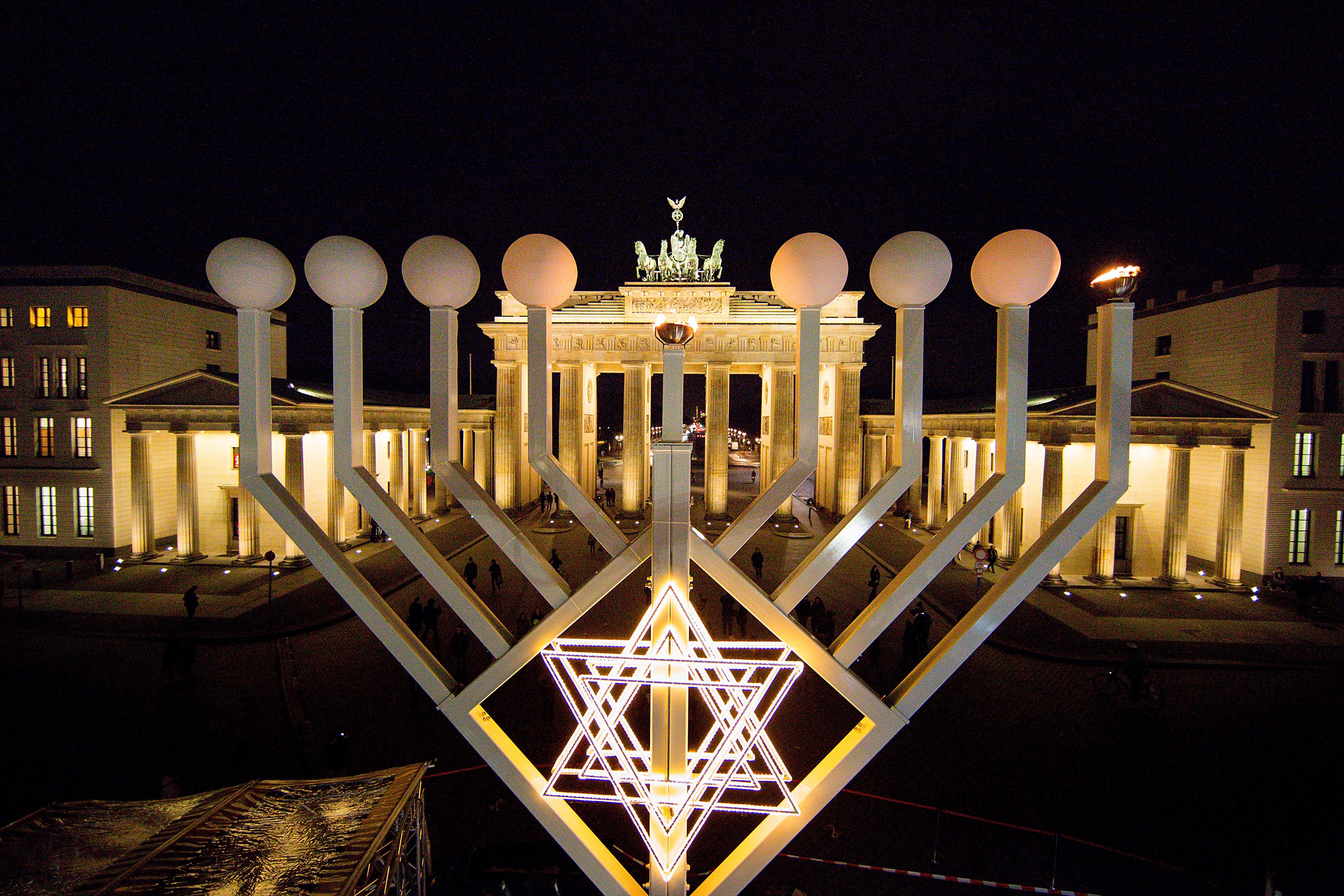 a large menorah with a star of david photographed at night with an ornate building behind it