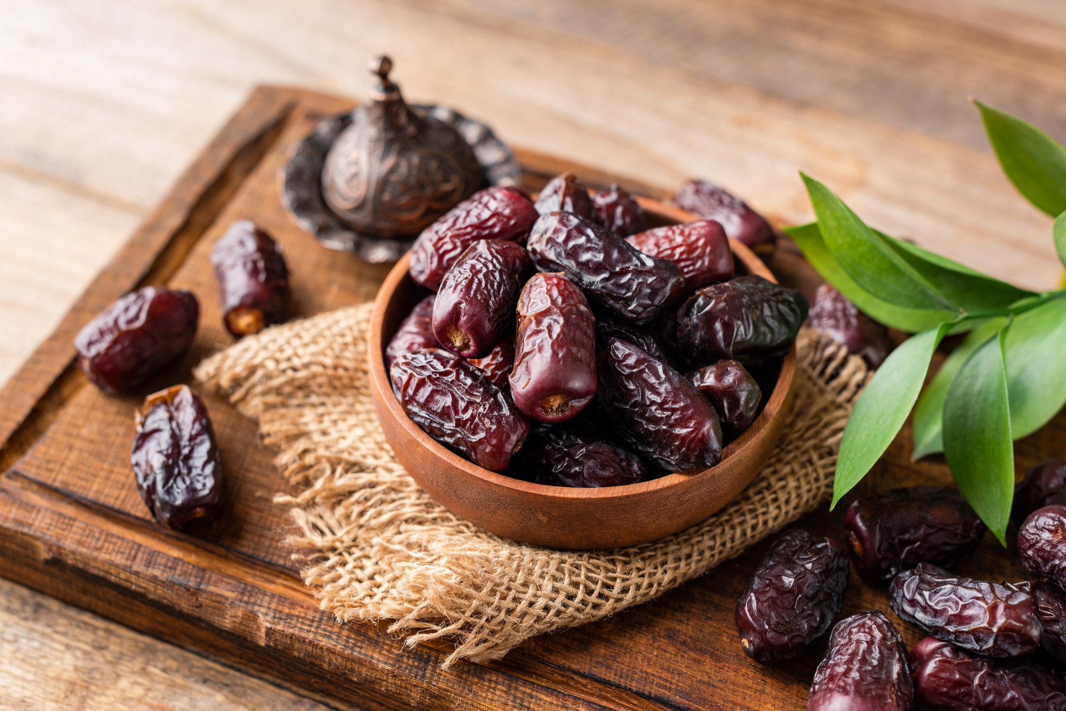 A bowl of dates sitting on a wooden board.
