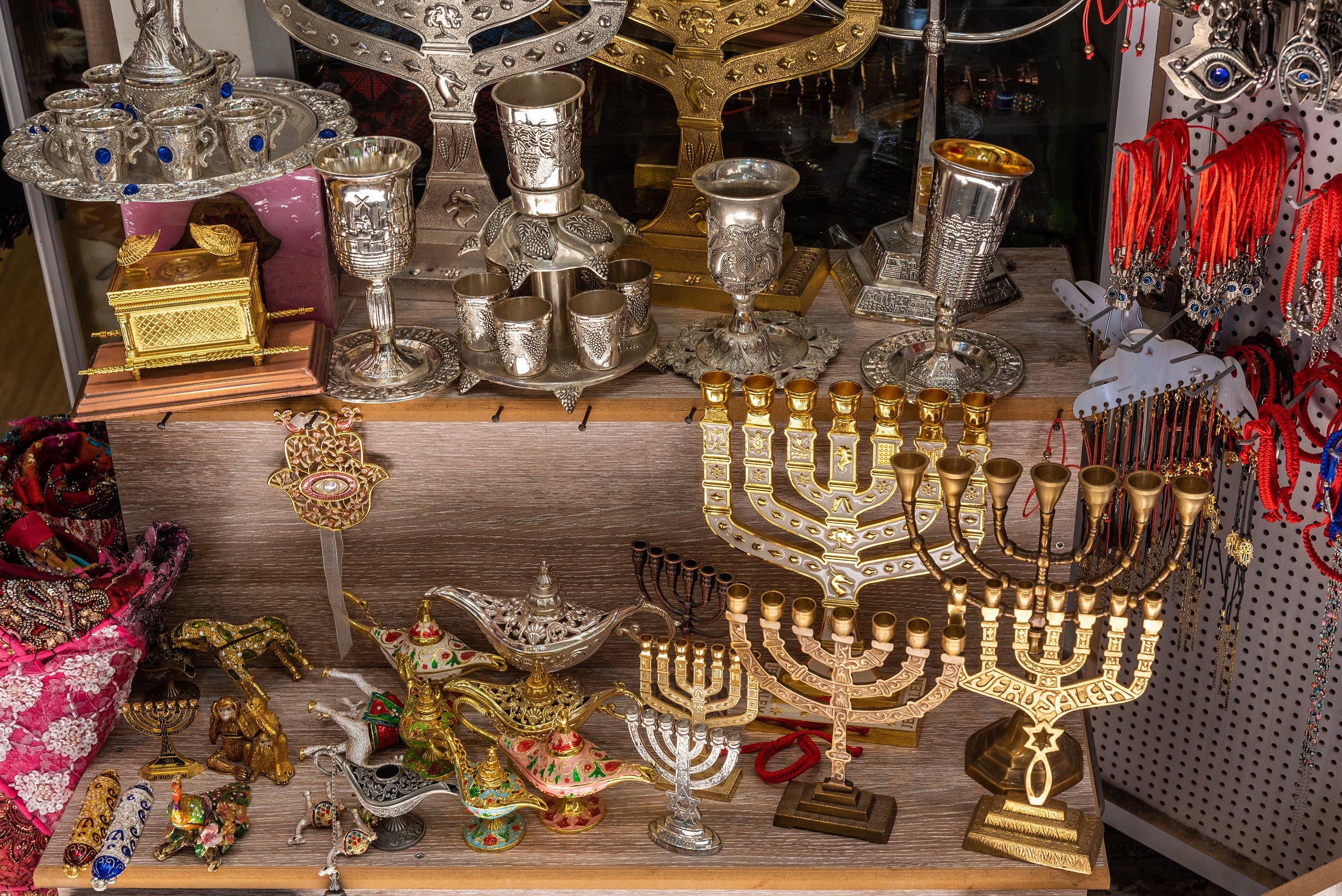 Menorahs and lanps and a tea set displayed on tables at an outdoor bazaar
