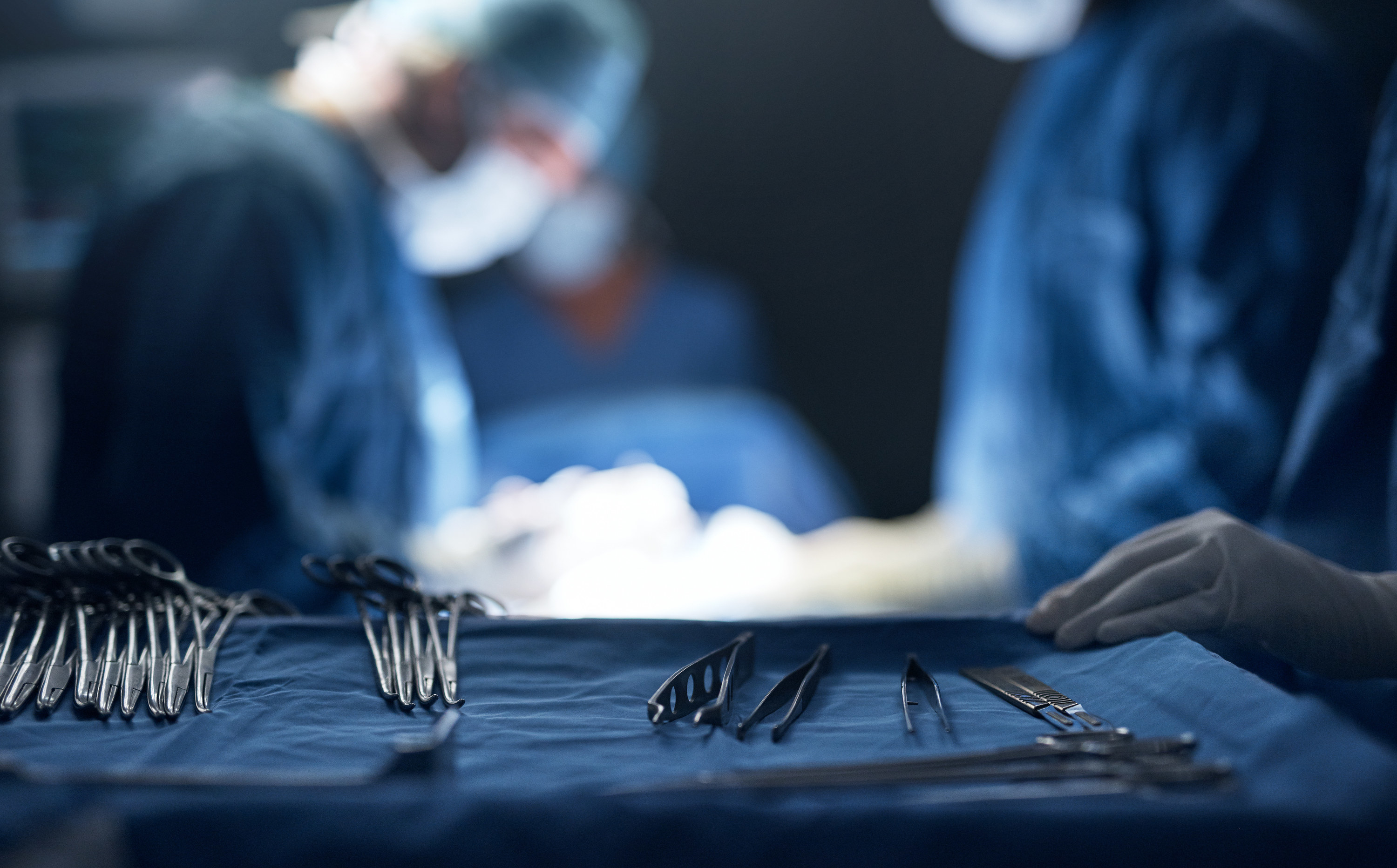 medical tools on tray while surgeon performs surgery