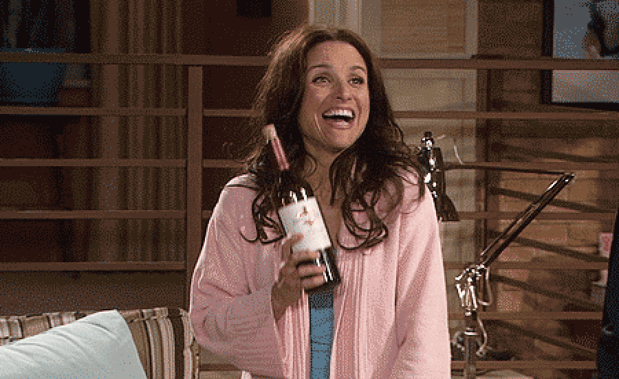 Julia louise dreyfus smiling with a wine bottle