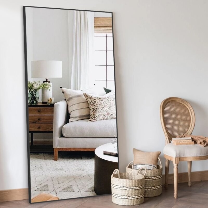 Mirror with black frame with baskets and a chair next to it