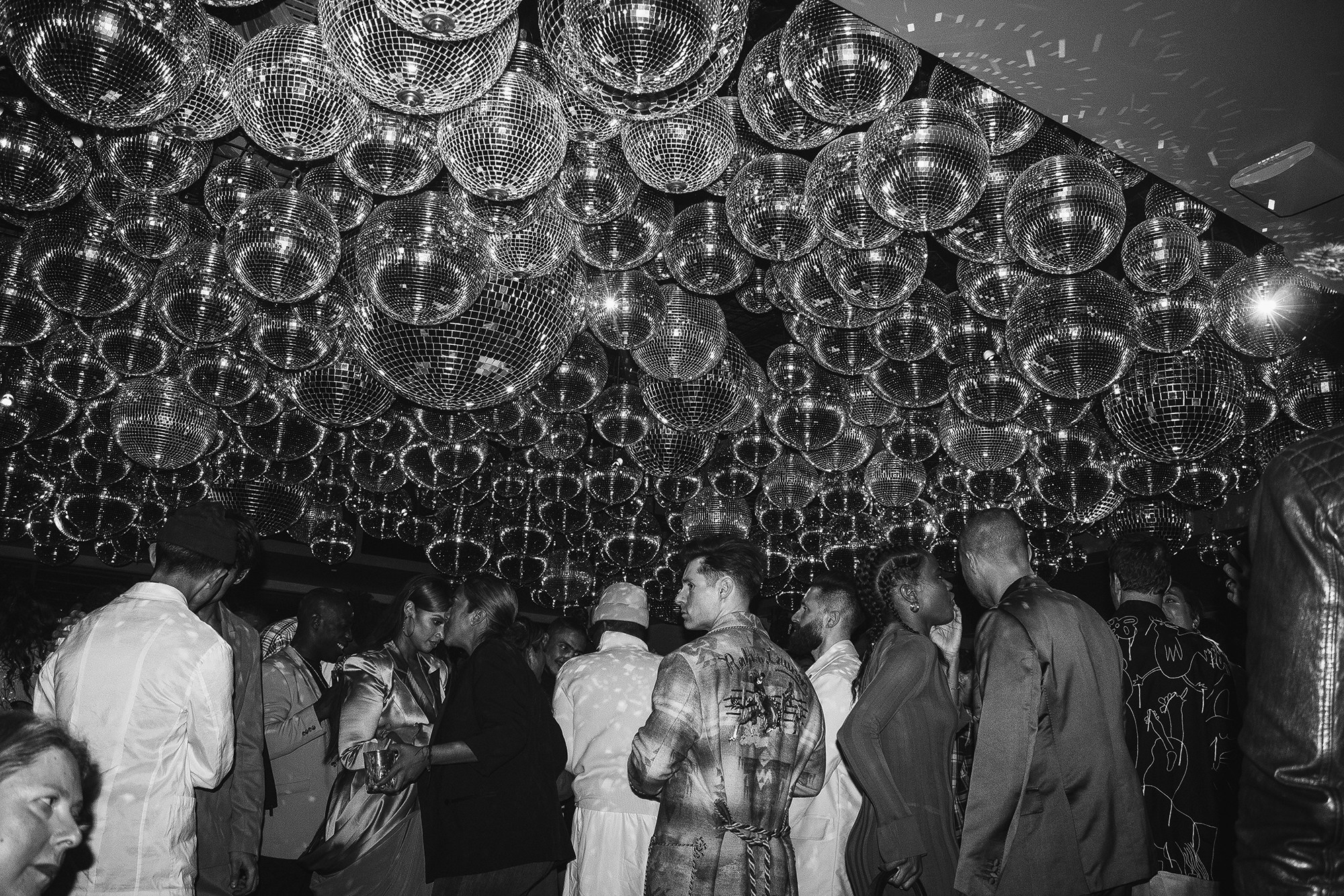 A crowded dance floor with dozens of disco balls on the ceiling