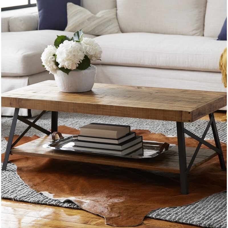 Coffee table shown in a living room, with accessories, rugs and furniture around it
