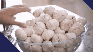 People reaching into a bowl of garlic