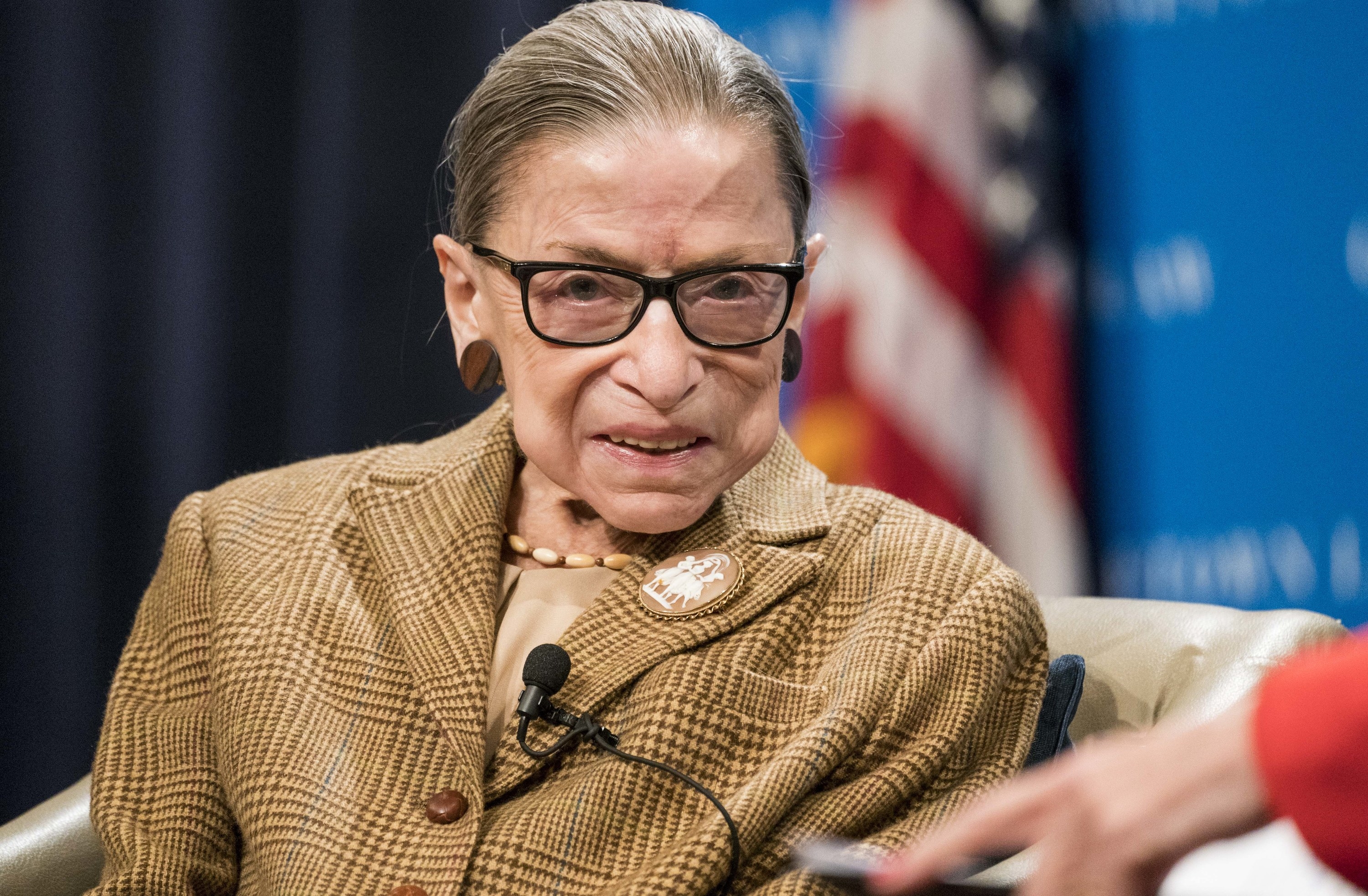 Ruth Bader Ginsberg wearing a tweed suit and smiling,