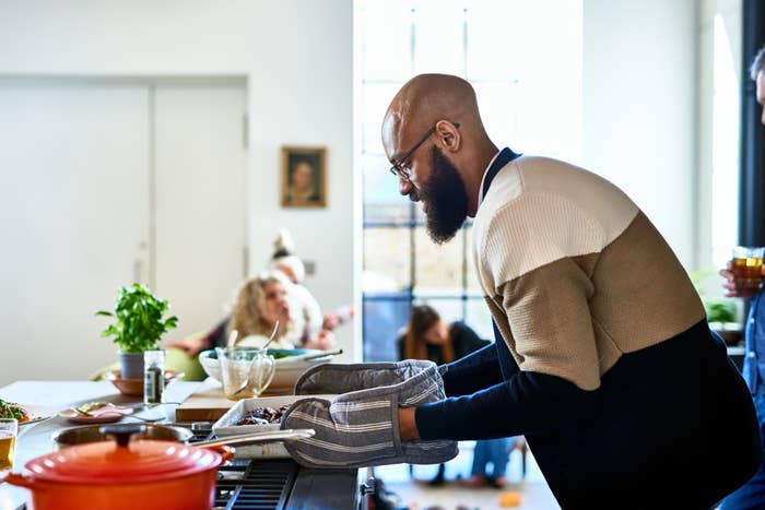 Person puts a dish from the oven on the stovetop.