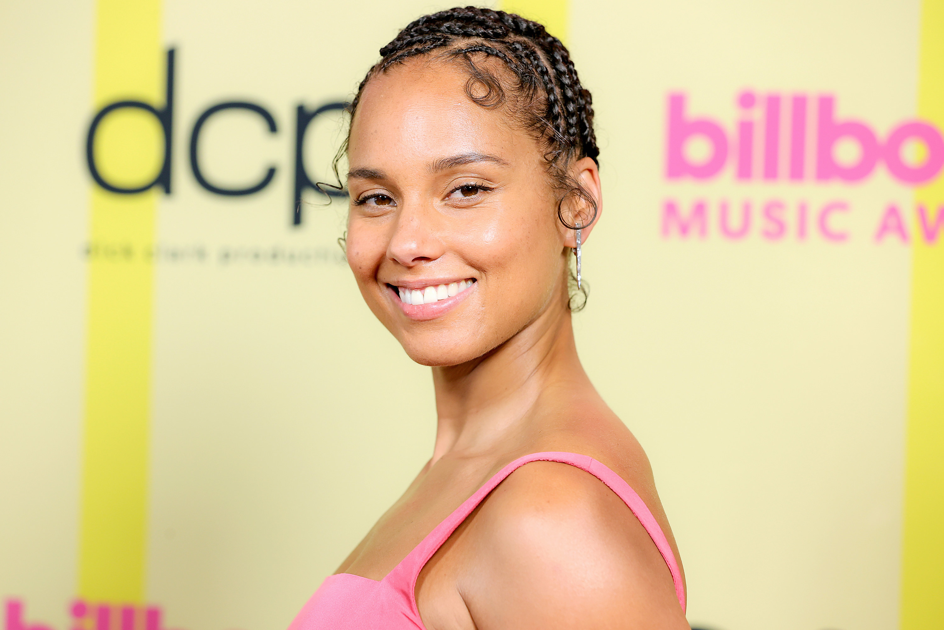 Alicia keys in a pink dress smiling and looking into the camera.