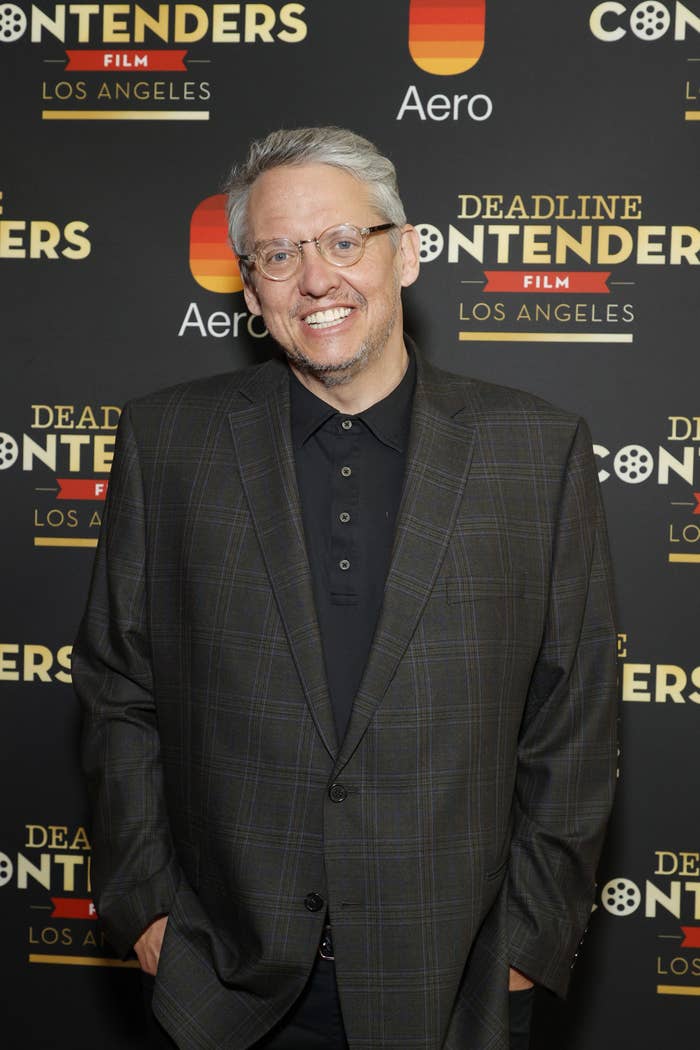 Adam McKay smiles for a photo at a red carpet event while wearing a suit jacket