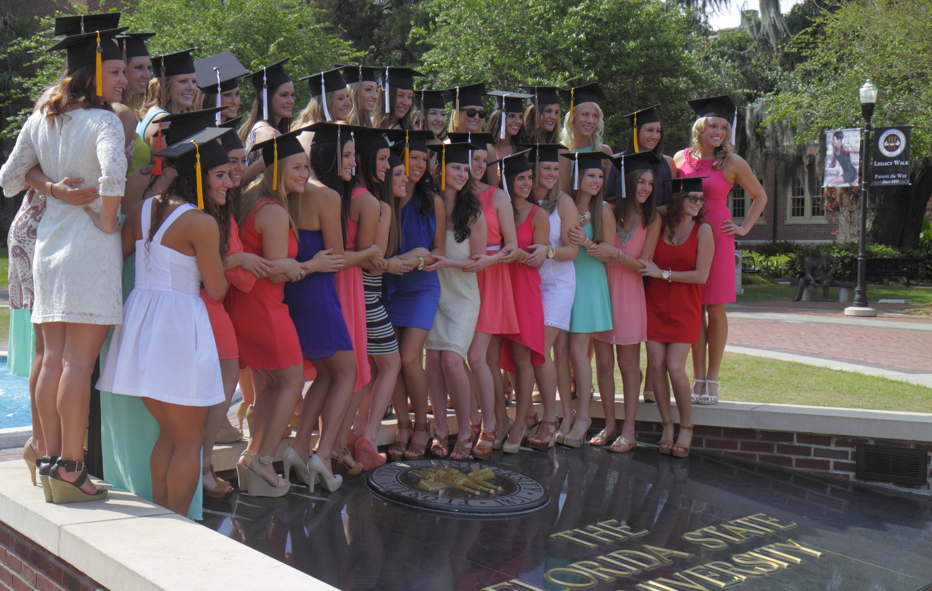 A group of girls standing next to each other posing at their college on graduation day