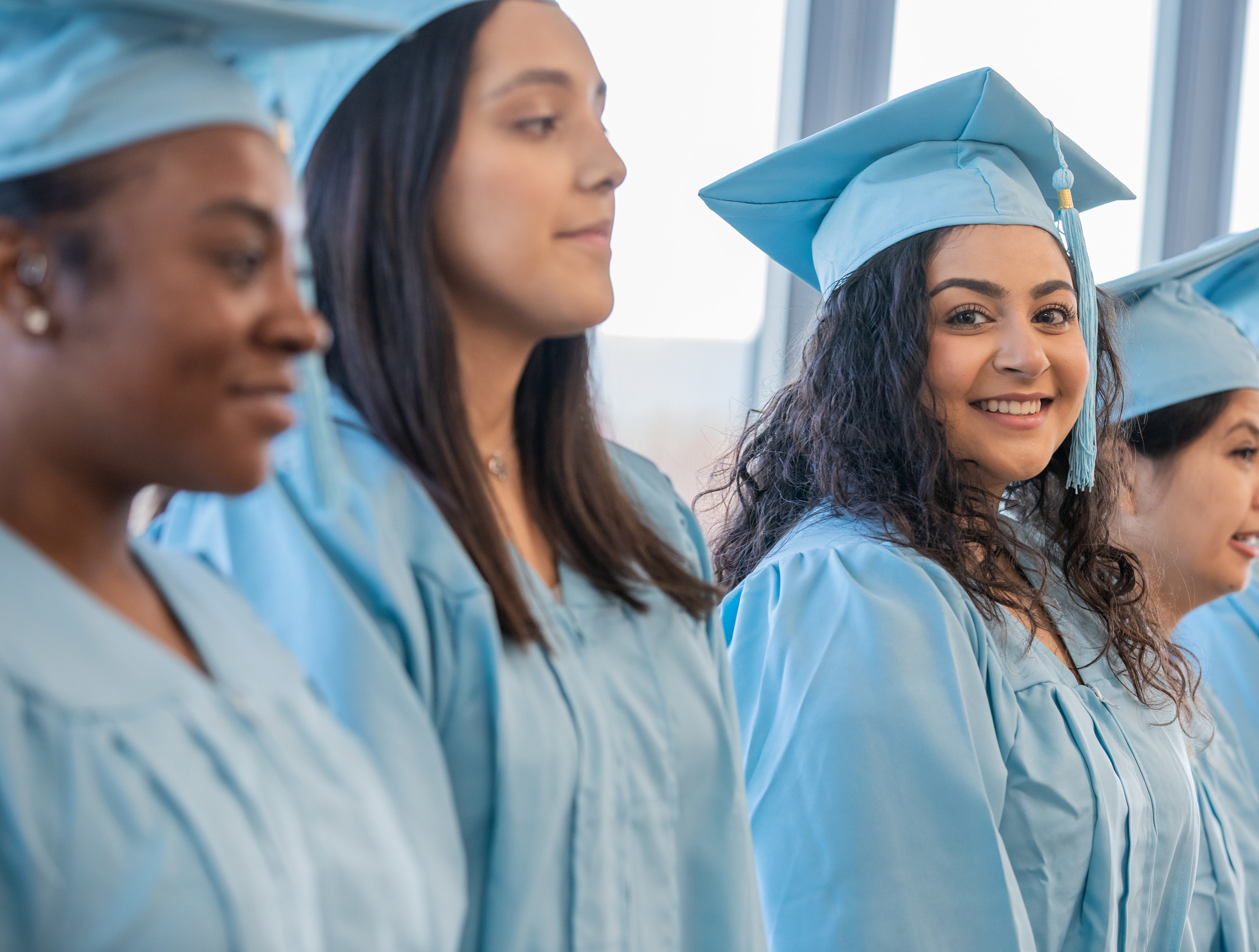 A group of girls standing next to each other in blue graduation caps and gowns