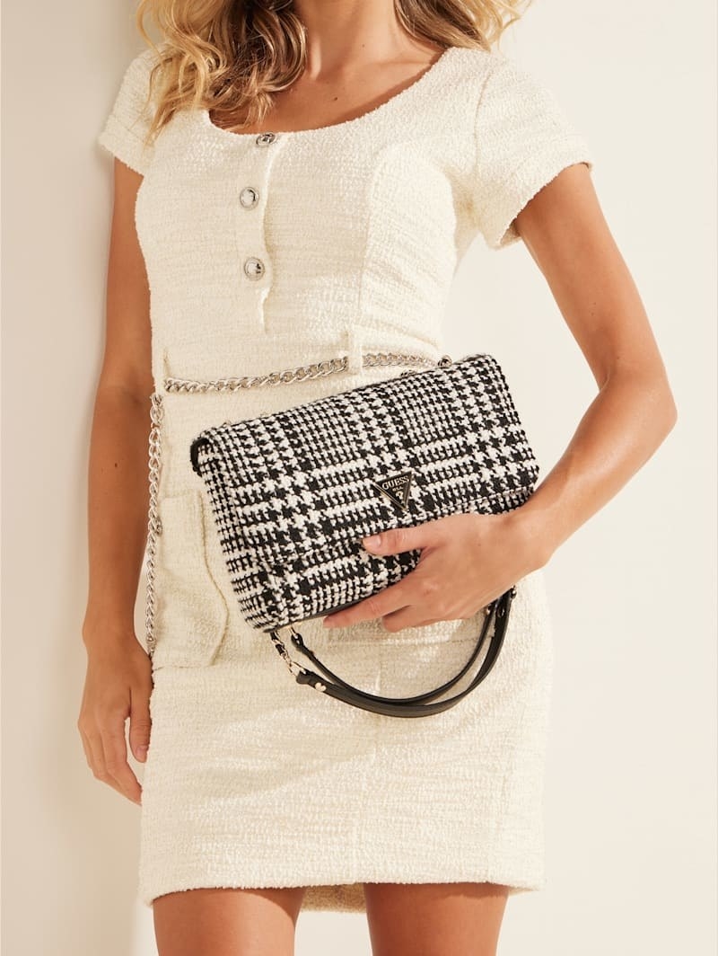 a model holding a black and white tweed crossbody bag