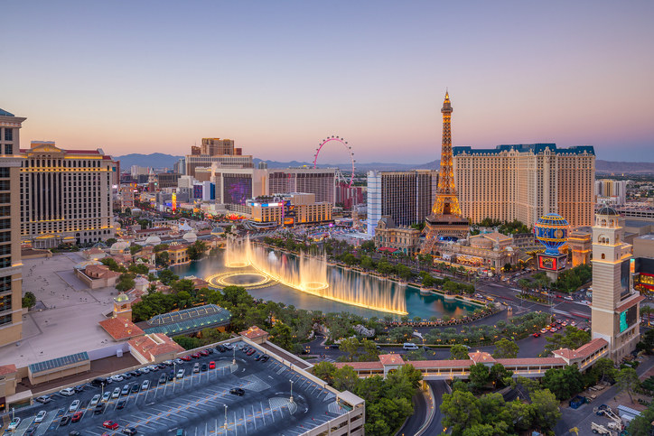 shot of Las Vegas, featuring the city&#x27;s ferris wheel, hotels, famous fountain, and Eiffel Tower replica