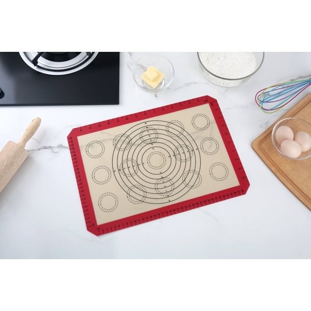 The silicone mat on a kitchen counter next to cooking supplies.