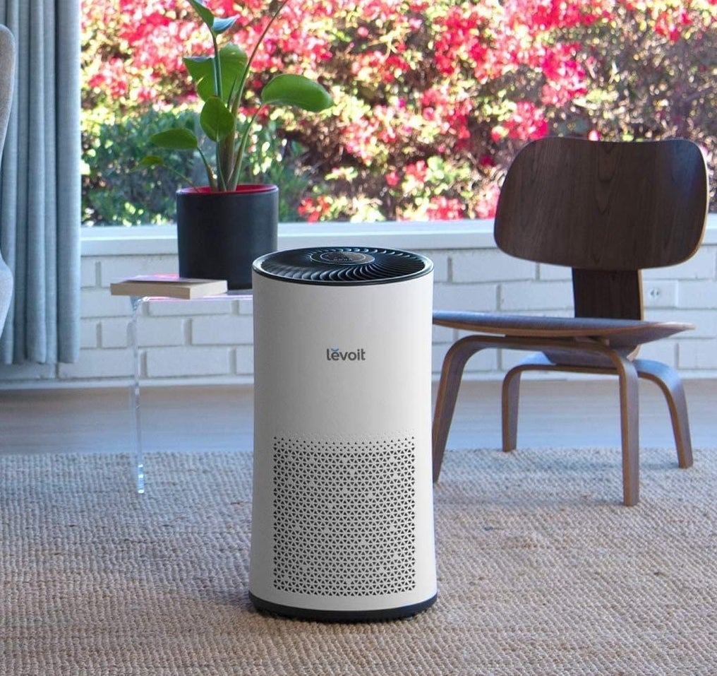The air purifier on a carpet in front of a chair