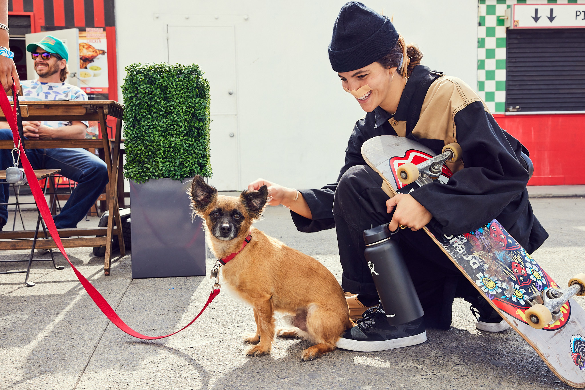 Skater and influencer Brooklinn Khoury kneeling with her skateboard and petting a small dog